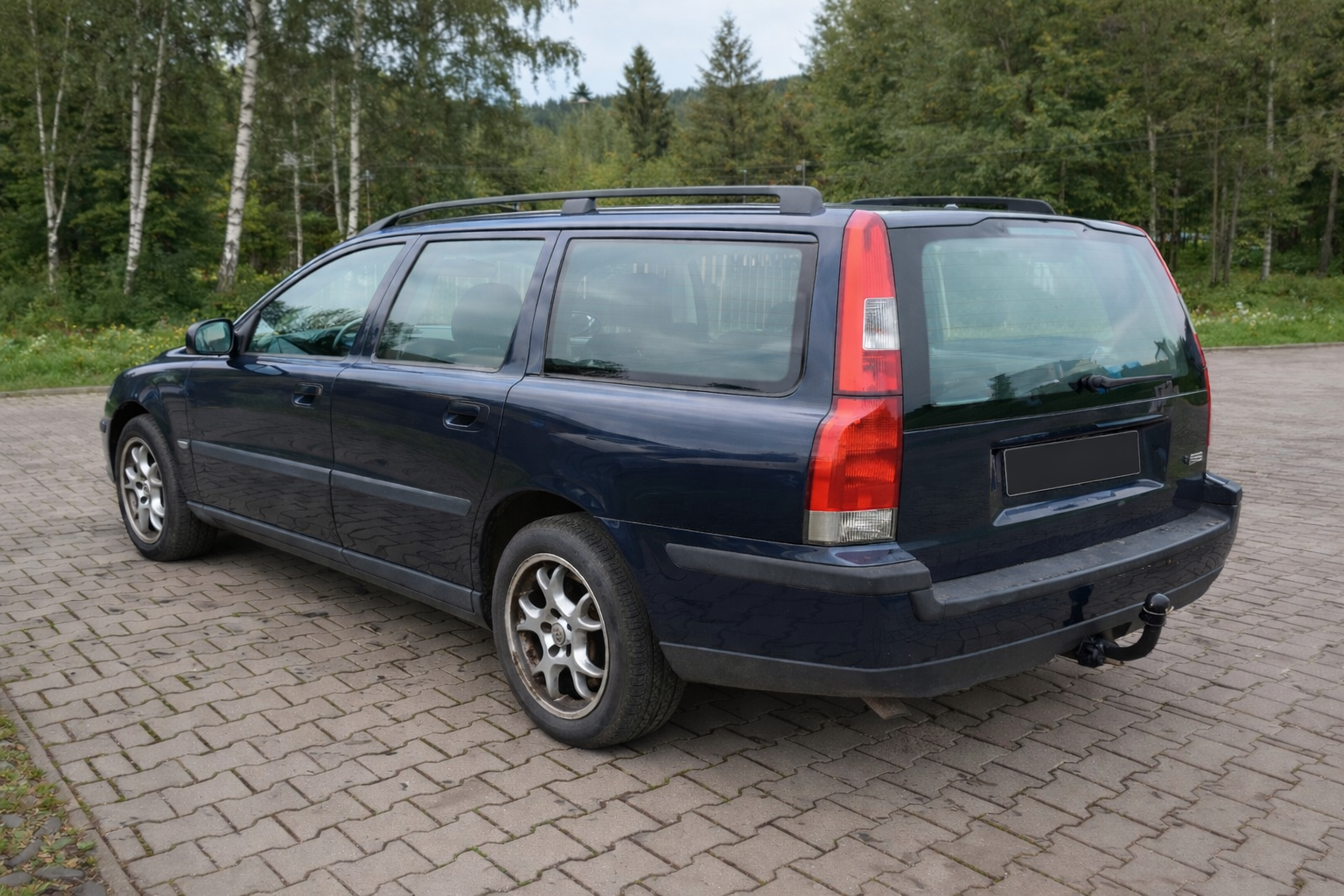 Tumša zilā Volvo V70 meža ceļā